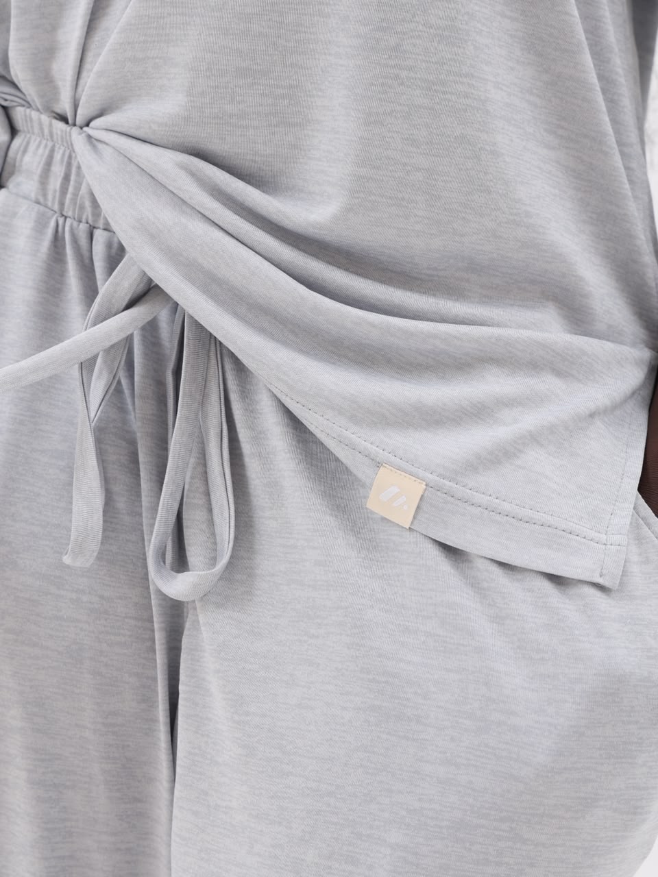 Close-up of the drawstring waist, side pocket and brand label in silver grey